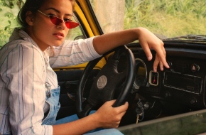 A young woman sitting behind the wheel of a car